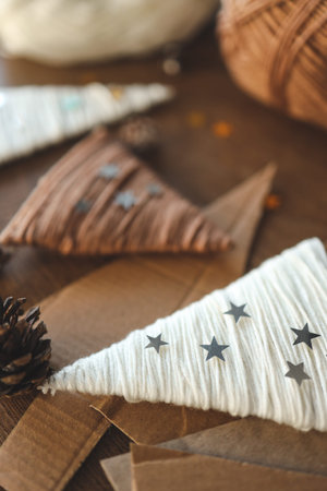 Christmas craft background with handmade yarn cone xmas trees in natural colors. DIY organic...