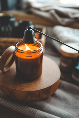 Aesthetic warm photo, candle extinguishing tool and burning candle.の写真素材