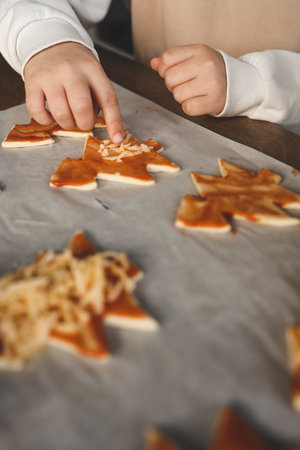 Child making pizza in the shape of a Christmas tree, activity idea.の写真素材