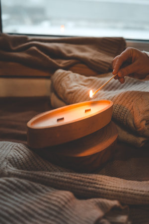 A match lights a candle in wood, stylish interior.