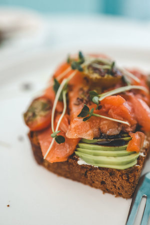 Healthy breakfast. Avocado toasts with salmon on ceramic plate.