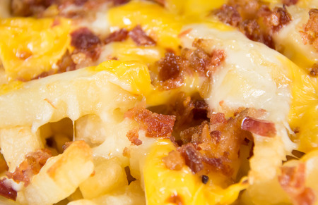Disco Fries - French fries topped with melted yellow cheddar cheese and sprinkled with bits of bacon, a closeupの写真素材