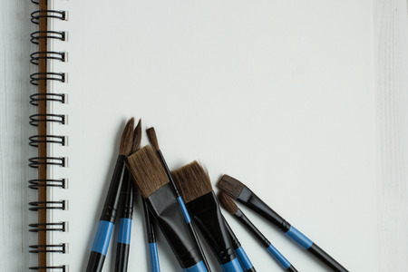 Paint brushes and empty sketchbookの写真素材