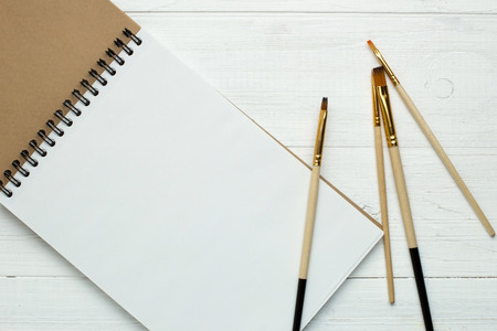 Paint brushes and empty sketchbookの写真素材