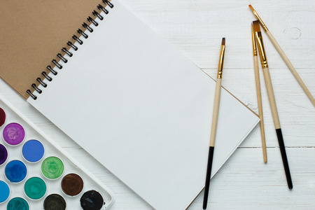 Paint brushes and empty sketchbookの写真素材