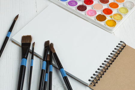 Paint brushes and empty sketchbookの写真素材