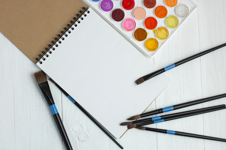 Paint brushes and empty sketchbookの写真素材
