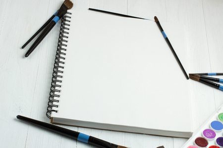Paint brushes and empty sketchbookの写真素材