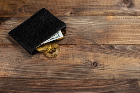 Money and Crypto-currency in the physical purse. The concept of virtual money in the wallet. On a wooden table.の写真素材