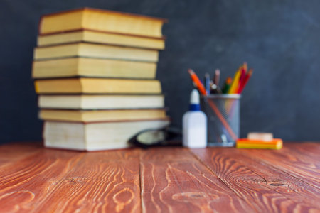 Textbooks and school supplies on a table, against a chalkboard background with chalk. Concept of...