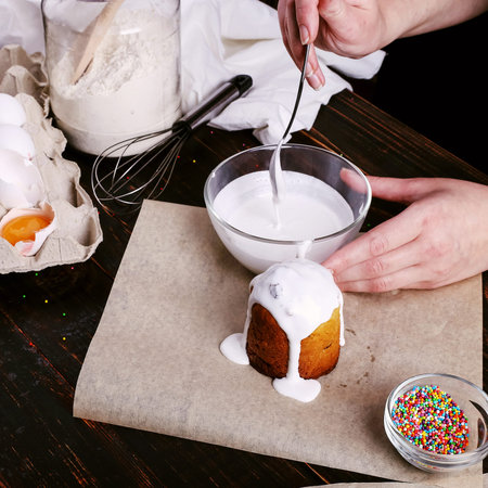 The girl prepares Easter baking, smears the cake with icing and sprinkles with colored powder....