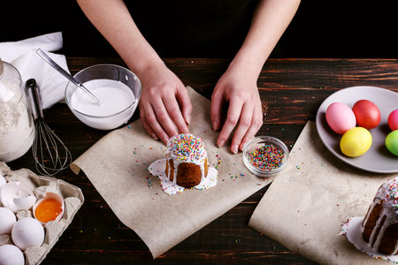 The girl prepares Easter baking, smears cake with icing and sprinkles with colored powder. Preparing...