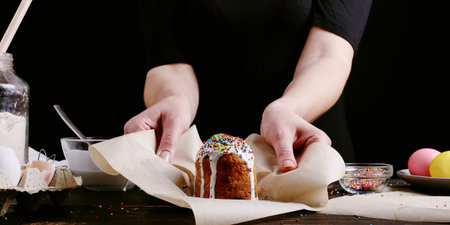 The girl is holding Easter baked goods with icing and colored powder. Preparing for the holiday on...