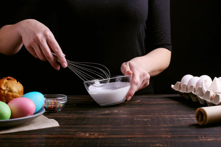 The girl prepares Easter baking, smears the cake with icing and sprinkles with colored powder....