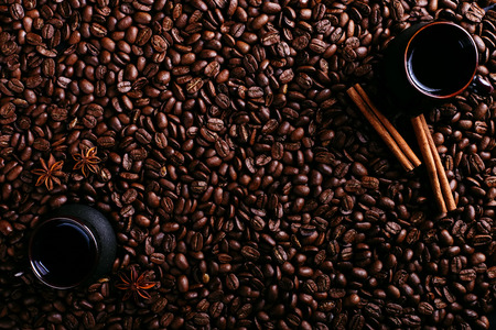 Two cup of coffee, star anise, cinnamon on the background of coffee beans. Fragrant spices for a drink, top view.の写真素材