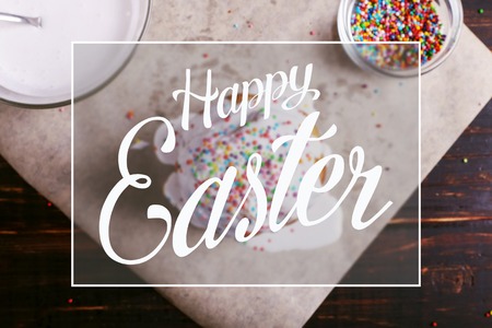 Easter baking with icing and colored powder and eggs. Preparing for the holiday on the kitchen table, on dark background.の写真素材