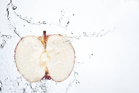 Fresh split red apple underwater with bubble trail on white backgroundの写真素材