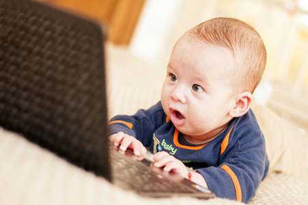 Four months baby with laptop at homeの写真素材