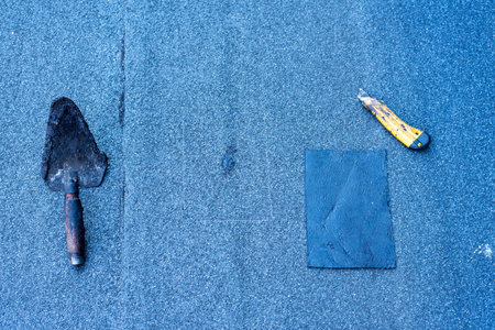Roofer making repairs waterproofing of the roof, welding patches by using a propane  gas burner and...