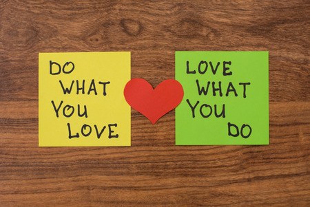 Yellow and green note paper with red heart on rustic wooden background. 'Love What You Do and Do What You Love' notes pasted on blackboard.の写真素材