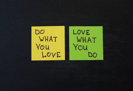 Yellow and green note paper on black wooden background. 'Love What You Do and Do What You Love' notes pasted on blackboard.の写真素材