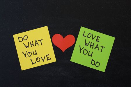 Yellow and green note paper with red heart on black wooden background. 'Love What You Do and Do What You Love' notes pasted on blackboard.の写真素材