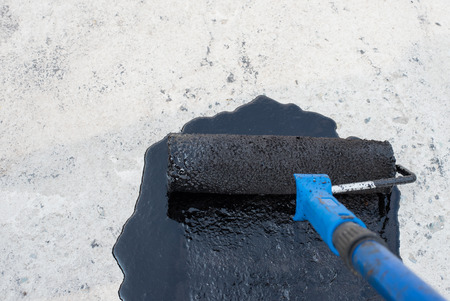 Worker covered surface, bitumen primer for improving adhesion during surfacing,  rolled waterproofing, during the installation of isolation on industrial or household objectsの写真素材