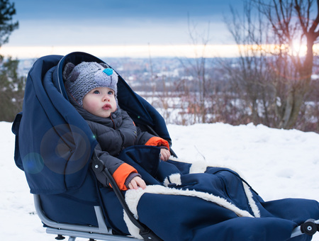 Little boy sitting in a sleigh. Cute little boy sitting on her sledge in winter day. Winter play, snow, sledding - beautiful boy has a fun on snow. Little  boy enjoy a sleigh ride.Outdoor fun for family Christmas vacation.の写真素材