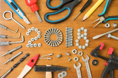 Happy new year 2018 composition with screws, nails,  bolts , dowels and tools on wooden background. New year. New year background.の写真素材