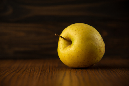 Yellow apple on the wooden vintage backgroundの写真素材