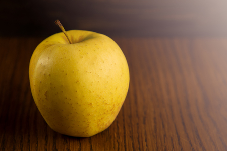 Yellow apple, on the dark wooden background.の写真素材
