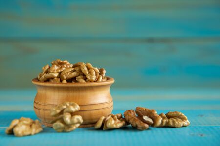 Walnuts on blue rustic table in wooden bowlの写真素材