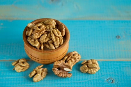 Walnuts on blue rustic table in wooden bowlの写真素材