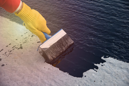 Worker applies bitumen mastic on the foundation