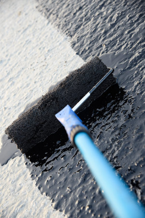 Worker applies bitumen mastic on the foundation