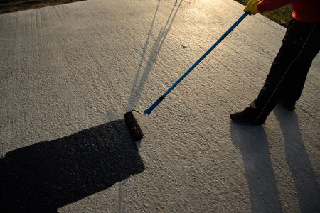 Worker applies bitumen mastic on the foundationの写真素材