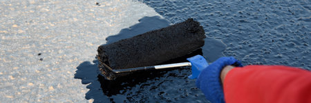 Worker applies bitumen mastic on the foundation