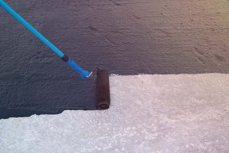 Worker applies bitumen mastic on the foundation