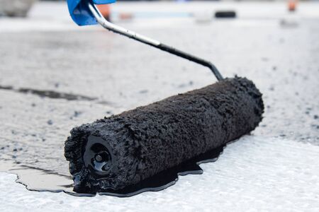 Worker applies bitumen mastic on the foundationの写真素材