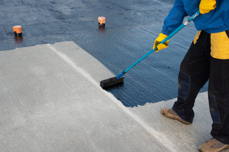 Worker applies bitumen mastic on the foundation