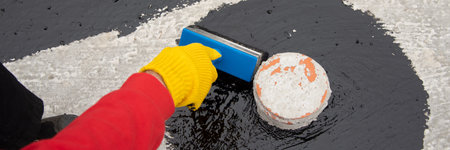 Worker applies bitumen mastic on the foundation