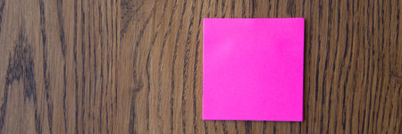 Pink stick notes on wooden background.