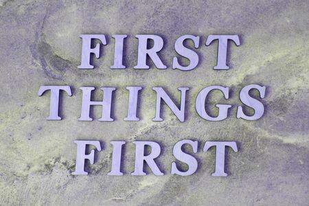 first things first , writen wooden letters on stone backgroundの写真素材