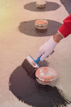 Worker applies bitumen mastic on the foundationの写真素材