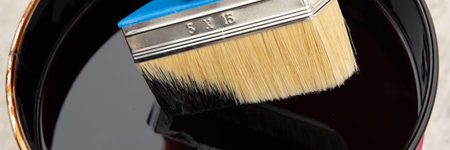 Roofers hand holding a brush with bituminous mastic