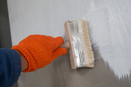 A worker is applying waterproofing paint to the wall. Applying a waterproofing mixture to the wall. Wall waterproofing on fasade. Worker adding ater resistant, protective coating.の写真素材