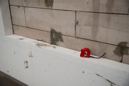 Red measuring tape on white rigid polyurethane foam sheet on wall. Thermal insulation. Selective...