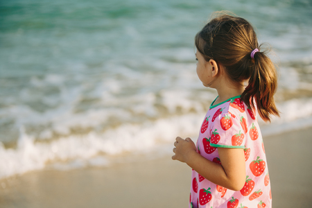 Little girl on the beach looking to the unknownの写真素材
