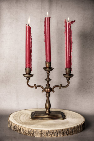 vintage candlestick with three red candles on a wooden standの写真素材