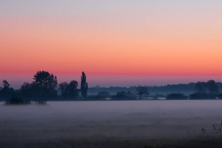 The setting sun over a misty meadowの写真素材